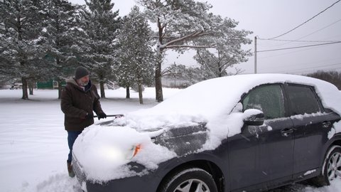 Cleaning off a car of snow after a winter blizzard