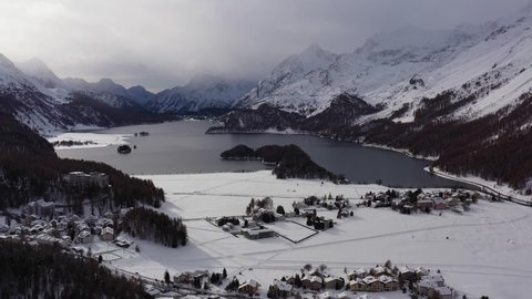 Aerial drone footage of the Sils Segl Maria village by the Silsersee lake in winter in the Engadine valley in Canton Graubunden in the Swiss alps. Shot with a rotation motion