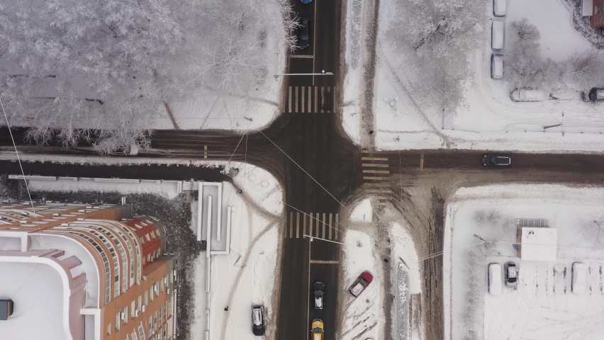 A taxi car drives through the snow-covered streets of the city after a snowfall. The streets of the city are covered with snow. Aerial view