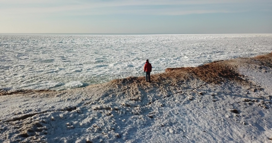 Aerial Footage of Man Standing on Shoreline of Frozen Lake Michigan