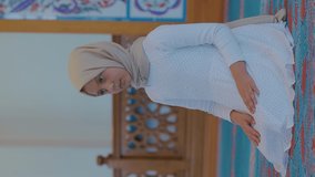 Little girl dressed in hijab prays in the mosque.Little girl praying to god alone.Video for the vertical story