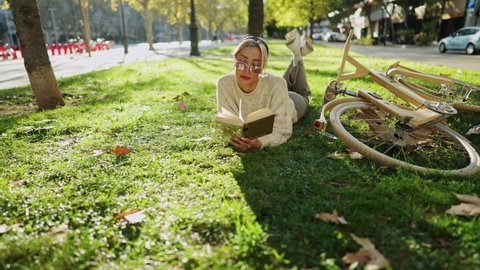 Woman reading book on grass near timber bicycle