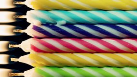 Vertical video colorful birthday candles row burning in timelapse on black. Rainbow background, multicolored melting wax burning candle shot in time-lapse. Happy Birthday, family holidays celebration