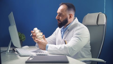 Online consultation in doctors office. Doctor demonstrates the departments of the spine vertebrae, hernia and it's injuries. Video call remote patient consulting. Medicine and health care concept