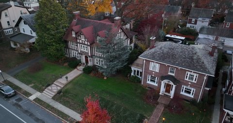 Aerial establishing shot of upscale expensive mansions in American suburb. Slow motion of car driving by on street. Birds eye view.