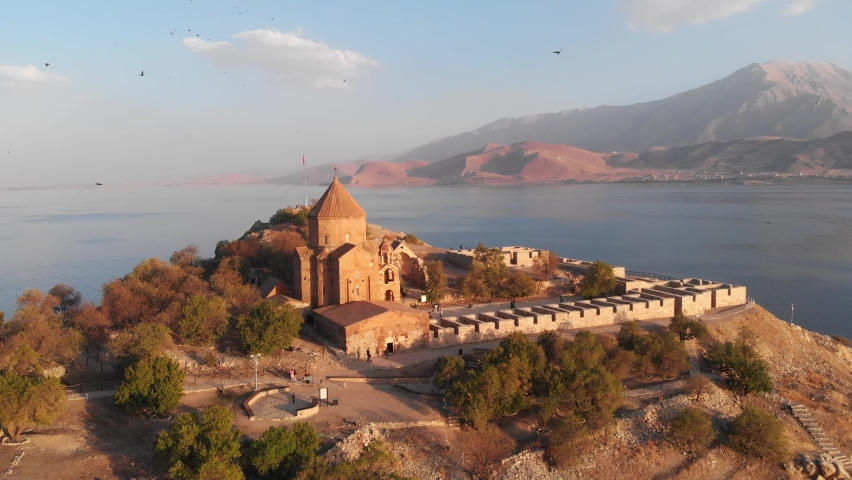 The Cathedral of the Holy Cross on Akdamar Island at Van lake in Eastern Anatolia, Turkey. Aerial view of the historic medieval Armenian Apostolic cathedral on Van lake in Turkey | Shutterstock HD Video #1084137025