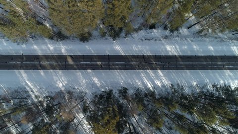 Aerial top down view abstract asphalt road snowy way route among winter green spruce forest of pine, Cars driving. Active road traffic. Cinematic countryside rural landscape. To make movie footage