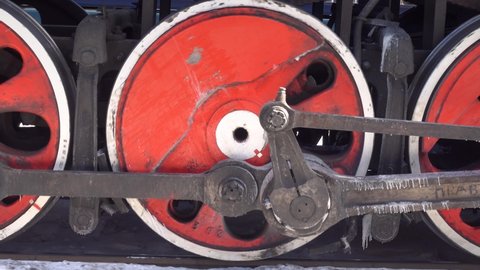 Powerful steel wheels steam engine, old steam locomotive, historic train details close-up. Train in motion departs from station on rails. Winter frozen icicle frost. Steam power plant. Gimbal footage