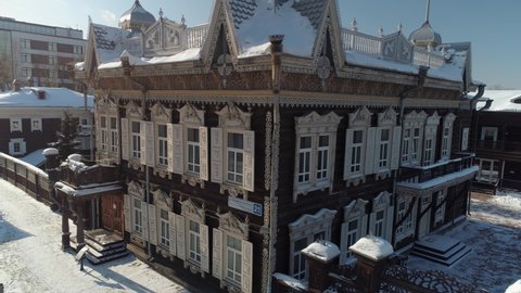 Irkutsk historical center of city, carved wooden merchant Shastiny tourist attraction house. Typical Russia baroque style shutters, authentic decorative home. Winter snowy cityscape. Aerial around. 4k