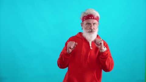 Adult gray-haired man in a red hoodie dancing to the music on a blue background, a cheerful man is filmed in a video for advertising.