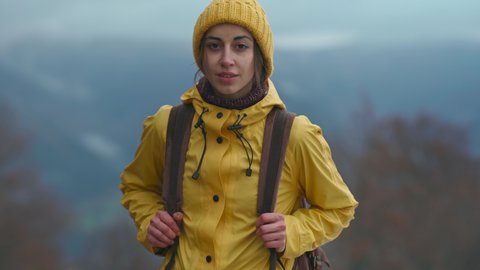 Beautiful woman in yellow wear stands in forest, looks straight, inhale and breathe in fresh after rain air. Travel adventure Scandinavian tourism concept. Roadtrip wanderlust mood.