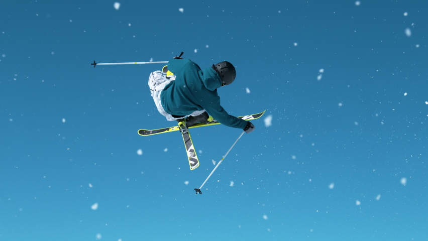SLOW MOTION, CLOSE UP: Freestyle skier takes off a big kicker and does a spinning grab trick with crossed skis. Cinematic shot of a pro skier doing tricks on a sunny winter day in the Julian Alps. | Shutterstock HD Video #1084147669