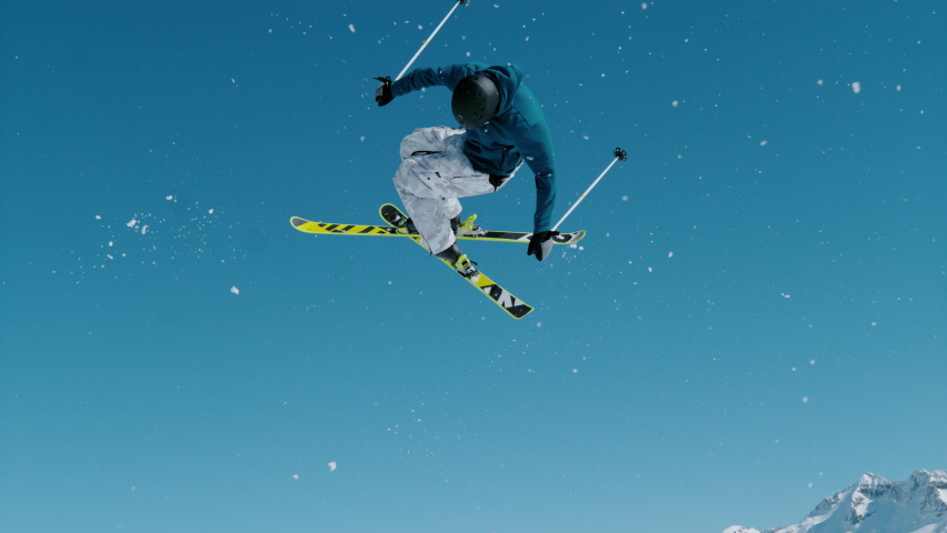 SLOW MOTION, CLOSE UP: Expert freestyle skier rides up a kicker and does a spinning trick on a sunny day. Athletic male tourist rides off a snowpark kicker in Vogel and does a spectacular 360 grab. | Shutterstock HD Video #1084147672