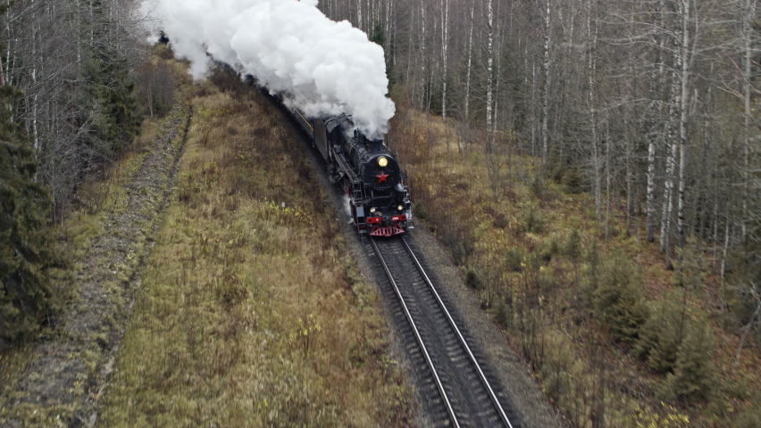 Aerial view of steam vintage locomotive pass over the forest. White Clouds of Steam. Aerial view. Autumn. | Shutterstock HD Video #1084148146