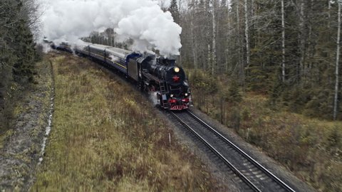 Aerial view of steam vintage locomotive pass over the forest. White Clouds of Steam. Aerial view. Autumn.