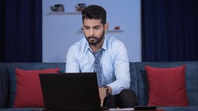 A bearded young man discussing a sales report on a video call with his colleagues. Handsome businessman in formals using his laptop to make a web call - online meeting, distant communication, remot...