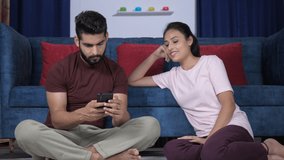A young couple in discussion - Checking mobile in leisure time . Happy husband-wife sitting together on the floor in their new house - comfortable, leisure time, surfing the internet - Powered by Shutterstock - Get 15% off with code: PIKWIZARD15