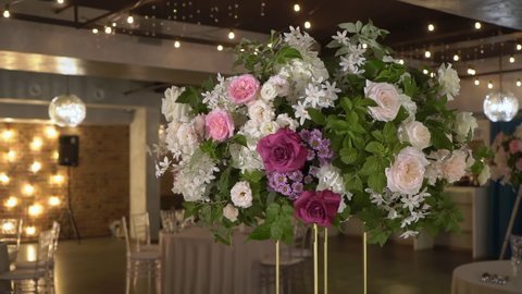PETERSBURG, RUSSIA - JULY, 24, 2021: Flower arrangement at the party. Decorated with white and pink artificial flowers at a wedding reception. Tables with food ready for holiday dinner.