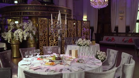 PETERSBURG, RUSSIA - JUNE, 26, 2021: Served table restaurant for dinner or celebration. White tablecloth, plates, napkins, glasses, chairs. Holiday indoors. Decorated with flowers and candles wedding.