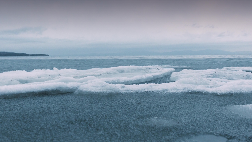 Frozen sea. The north Sea is not completely frozen yet and the ice floes are swaying on the waves. Gloomy weather on the horizon. Royalty-Free Stock Footage #1084155643