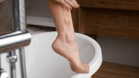 Bodycare Concept. Closeup Shot Of Unrecognizable Woman Scrubbing Legs In Bathroom, Young Female Rubbing Cosmetic Scrub To Skin, Making Anti-Cellulite Massage At Home, Cropped, Slow Motion Footage