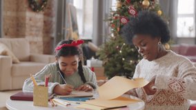 African American girl drawing picture and her mother cutting paper with scissors while making Christmas crafts together at home - Powered by Shutterstock - Get 15% off with code: PIKWIZARD15