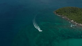 aerial drone shot of speed boat racing towards emerald bay in Phu Quoc island, Vietnam. Clear ocean water, beautiful summer day.