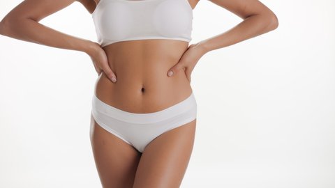 Horizontal medium shot of African American slim good-looking woman in white underwear strokes her body and puts her hands on her waistline on white background  After woman shaving concept