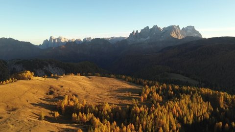 Drone flight over Fuchiade valley in Italian Dolomites countryside in autumn time. Wooden huts, orange larches forest and mountains peaks on background. Dolomite Alps, Italy. UHD 4k video