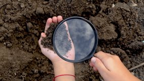 The child examines the soil with a magnifying glass. Selective focus. - Powered by Shutterstock - Get 15% off with code: PIKWIZARD15