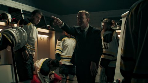 Happy cheerful talking to professional ice hockey team players on the locker room during the intermission. Motivation speech. Shoot with 2x anamorphic lens