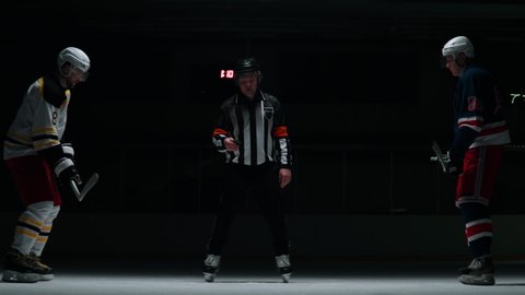 Dark staged shot of a referee running a face-off over central circle. Shot with 2x anamorphic lens