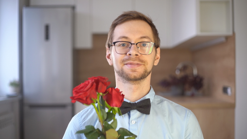 Passionate young male nerd in glasses and elegant outfit with bow tie holding red rose and looking at camera. Valentine's day concept. Royalty-Free Stock Footage #1084165456