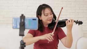 Asian female teacher teaching students how to play classical instrument violin from home via smartphone online video. Classical music education concept, study online from home. new normal life