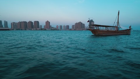 Doha, Qatar-December 2 2021: Katara eleventh traditional dhow festival in Doha Qatar sunset shot from sailing boat showing  dhows with Qatar Flag in Arabic gulf and Katara skyline in background