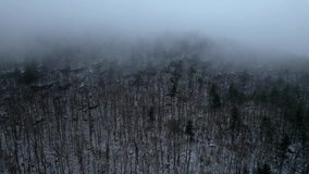 Aerial drone video footage of a beautiful snowy, foggy evening with low clouds in the Appalachian mountains during winter. This is in New York's Catskill mountain sub-range. 