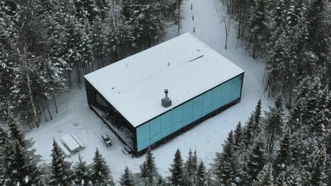 Luxurious Facility Of Reflexion Mirror Cabin During Snowstorm In Charlevoix, Quebec, Canada. Aerial Pullback