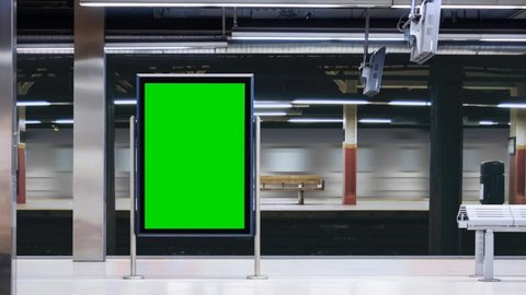 Empty modern billboard with a green screen for advertising, on a train station, blank billboard on subway station opposite the train arriving at the platform