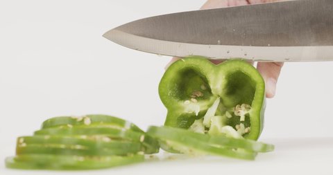 Chef uses a knife to cut green bell peppers. After cutting the remaining half slide into pieces.
