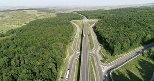 Aerial view of a landscape highway, Drone view of motorway in green fields light traffic, Vehicles on highway through scenic rolling green hills with trees and vegetation
