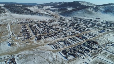 Winter snow-cowered old authentic village, wooden historic houses among mountains. Buryatia typical for Russia Siberia aerial countryside rural landscape. Baikal Territory tourist attraction. Travel