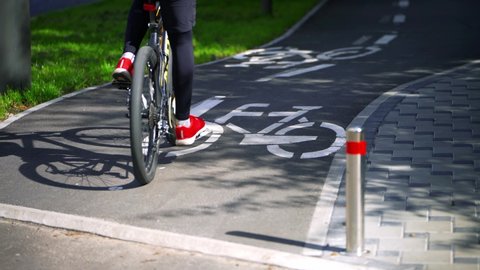 Young boy on a bicycle rides on a bike path in a city park. Bicycles riding in the bike lane. Cycling. Bicycle sign. Riding a bike on an asphalt road. 