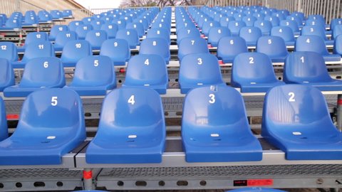Grandstand seats - numbered temporary retractable seating. Modular stands with numeration for audience on a stadium. Convertible and removable empty bleachers (plastic chairs) for a concert event.