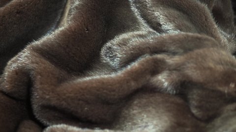 Mink Fur background. High quality Canadian black Fur clothes texture closeup. Soft and fluffy dark brown mink Texture surface Rotation. Slow motion. Macro shot. 4K UHD