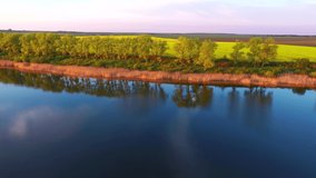 Splendid view of a calm lake and cultivated field in sunlight in the evening. Bird's eye view. Agricultural region of Ukraine, Europe. Cinematic drone shot. Filmed in UHD 4k video. Beauty of earth.