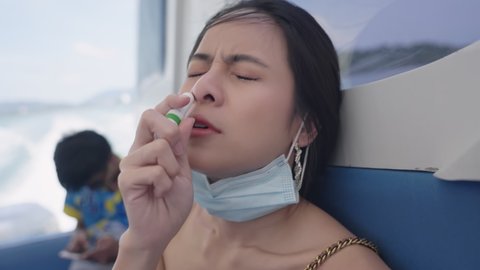 Young attractive asian female tourist having sea motion sickness symptoms while using speedboat transportation, a nausea woman breathing inhalation stick, alternative herbal treatment, summer holiday