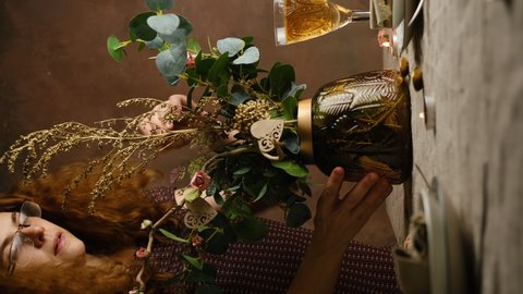 Young woman makes a flower arrangement for festive dinner on Valentine's Day. Romantic table setting, table decoration for Valentines Day. Vertical video.