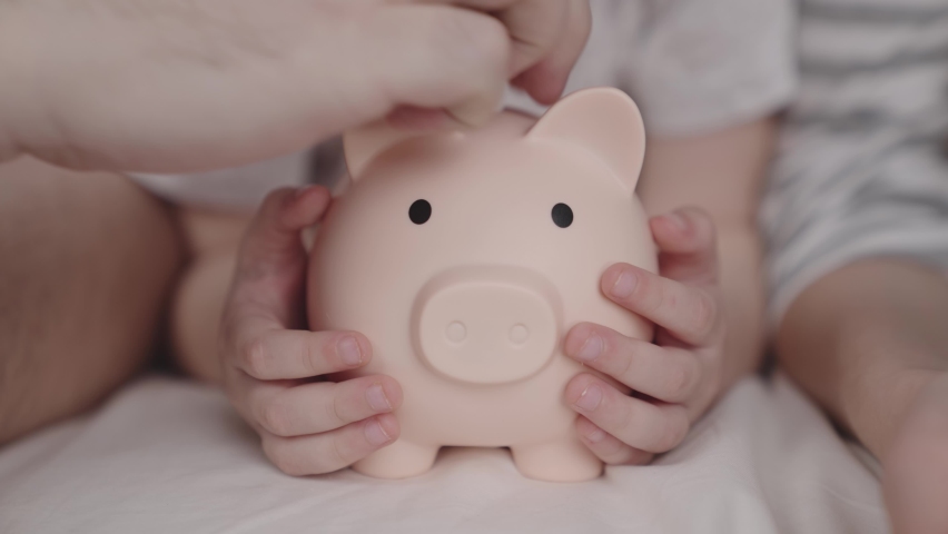 little child with mother and father throw coins of money at pig, happy family saving savings in piggy bank, childhood dream concept, little baby's home money, financial wealth savings, investing cash Royalty-Free Stock Footage #1084210855