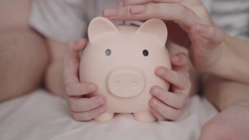 Little child with mother and father throw coins of money at pig, happy family saving savings in piggy bank, childhood dream concept, little baby's home money, financial wealth savings, investing cash | Shutterstock HD Video #1084210855