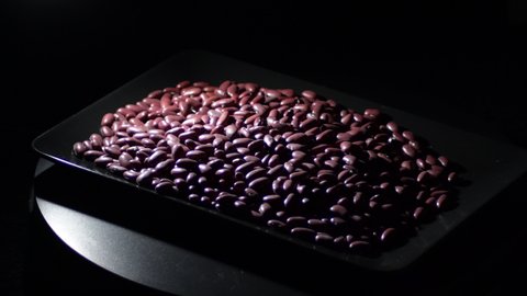 Red beans legumes in a black tray with a intimate light turning